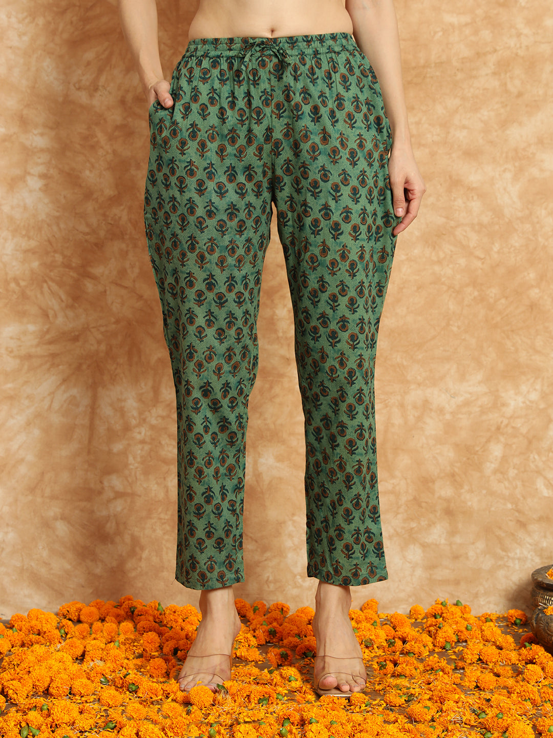 Green printed cotton pants for women with pockets, modeled on a floral marigold floor