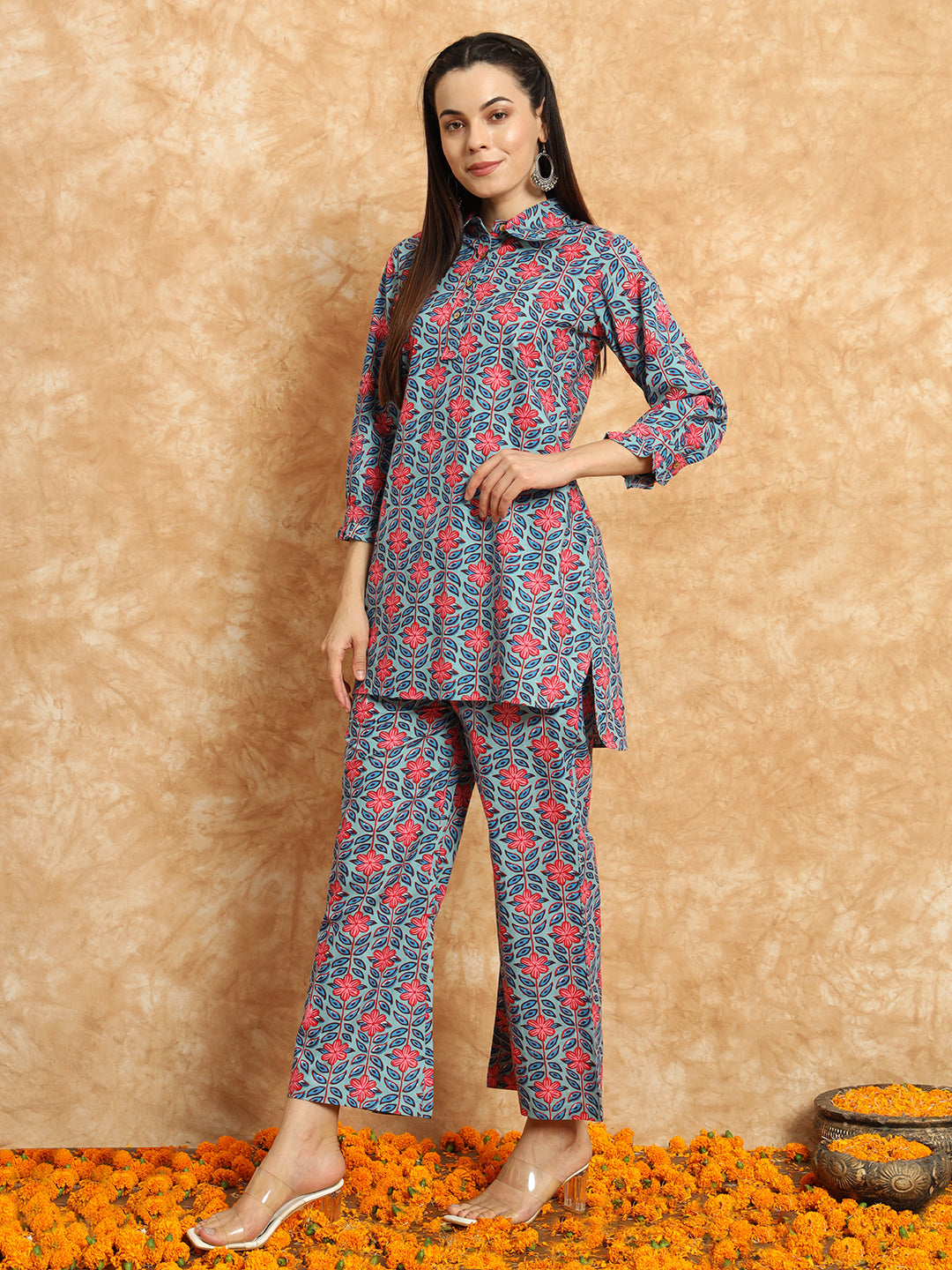 Woman in floral printed blue and red maternity kurta set, standing on marigold petals