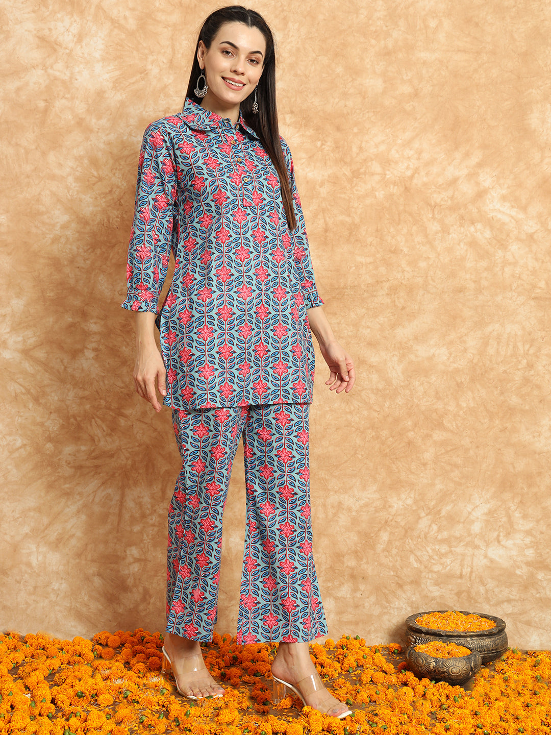 Woman wearing floral print maternity kurta set with wide-leg pants, standing on marigold flowers
