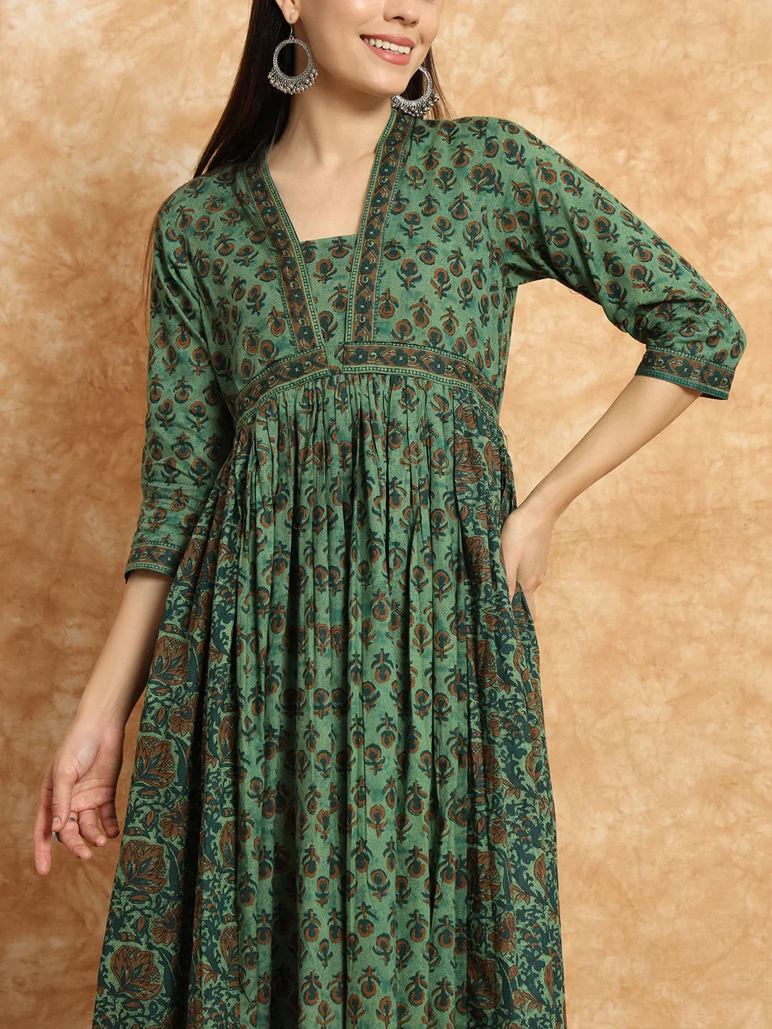 Woman wearing green printed maternity dress with three-quarter sleeves and ethnic earrings