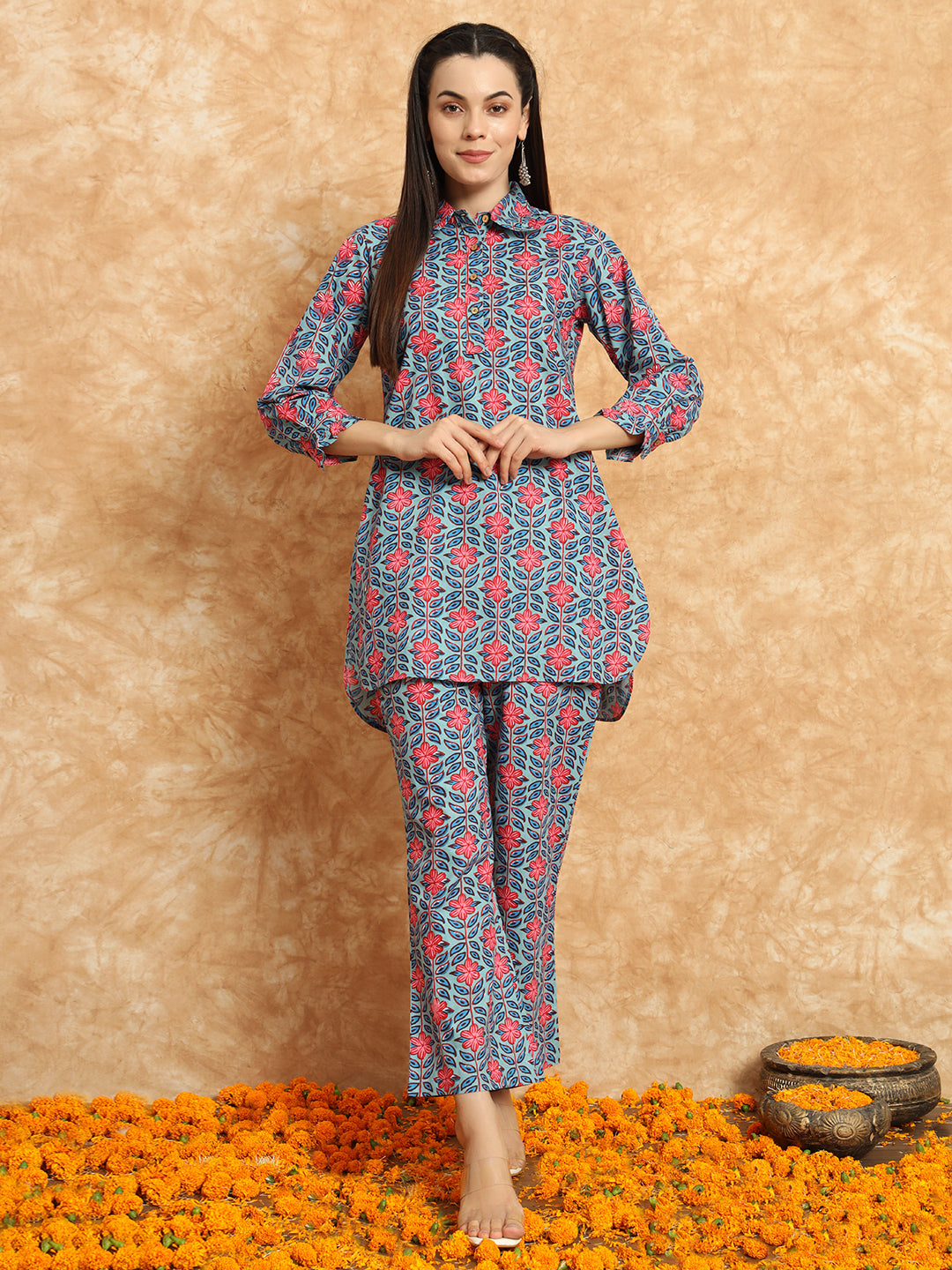 Woman in floral printed maternity kurta and pants set standing on marigold flowers indoors