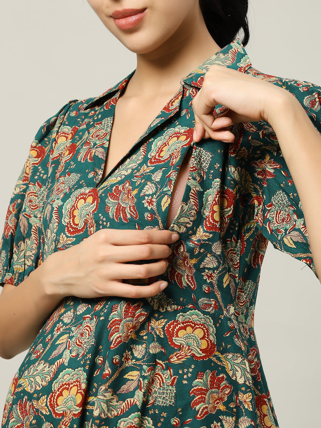 Woman in floral nursing dress showing concealed zipper for breastfeeding access