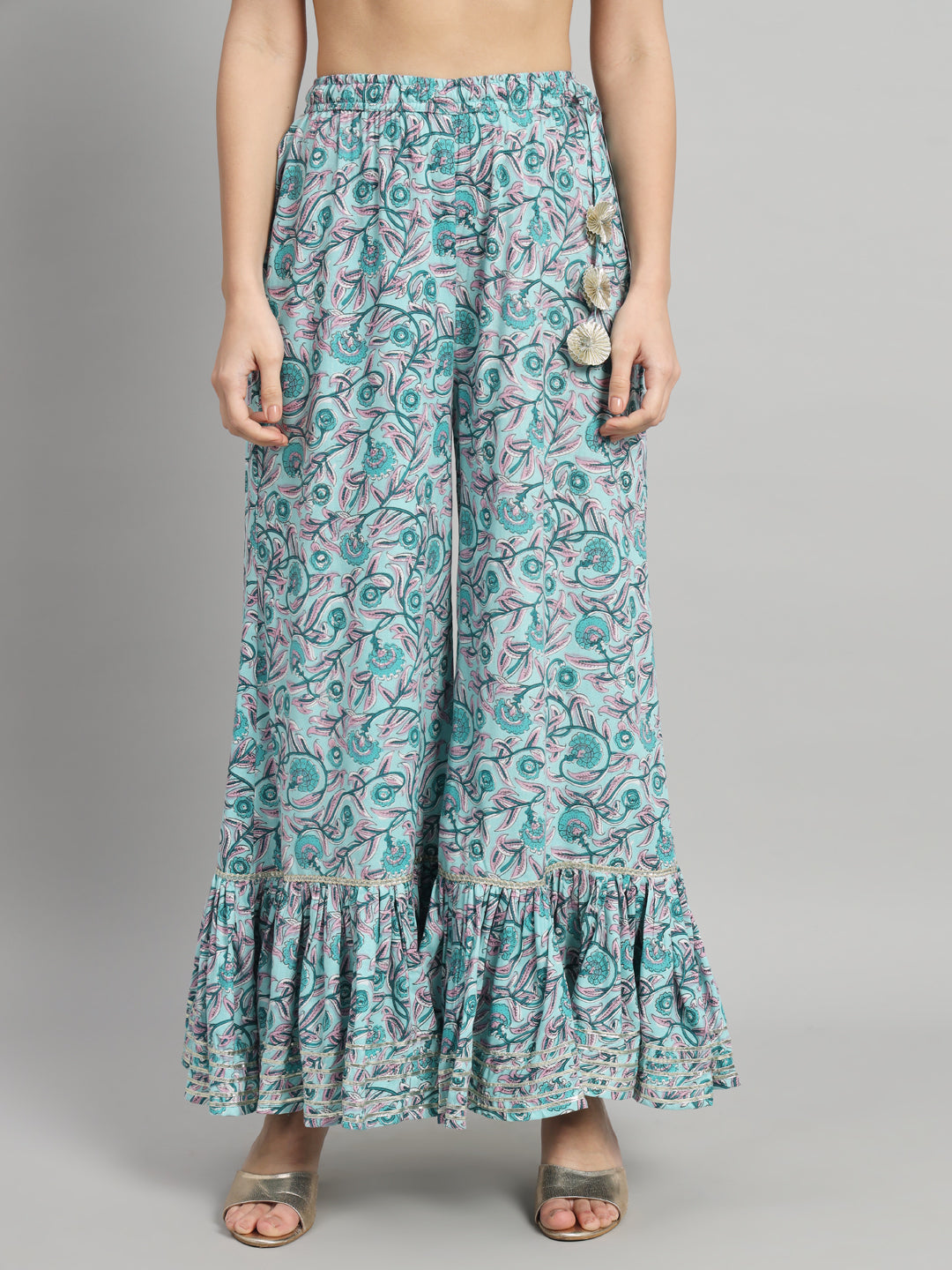 Woman wearing floral print wide-leg pants with ruffled hem and floral embellishments