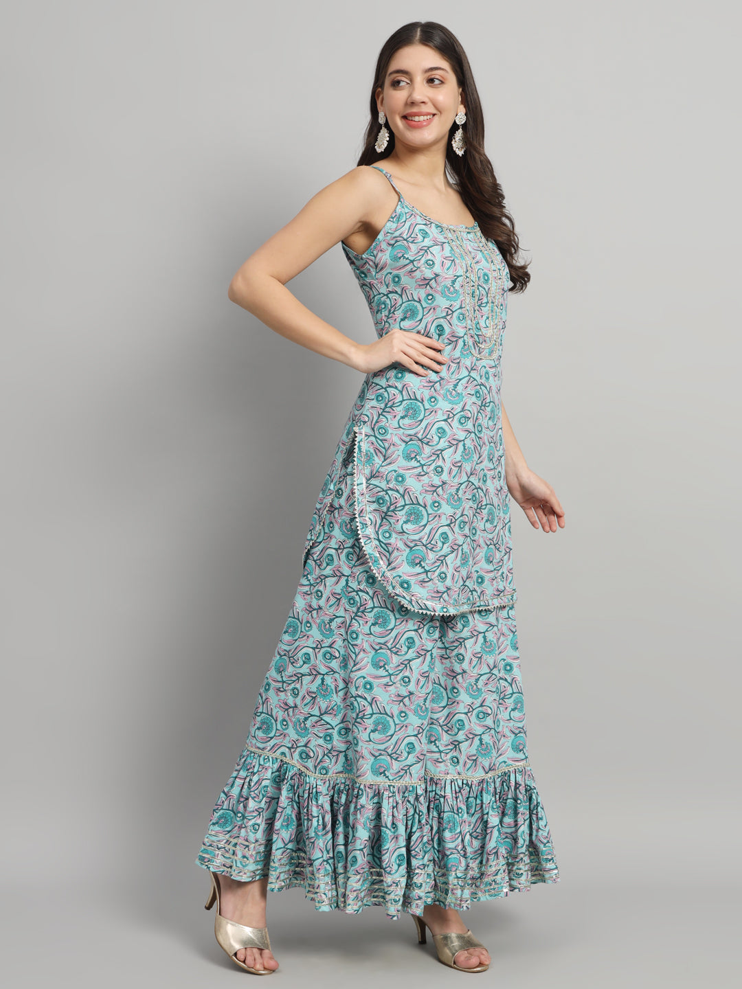 Woman in sleeveless blue printed maternity dress with ruffled hem, posing on grey background