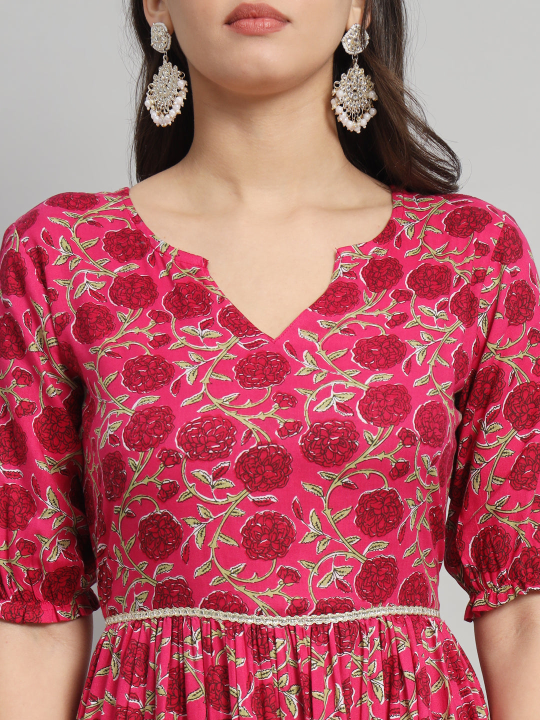 Woman wearing a pink floral maternity dress with puff sleeves and statement earrings