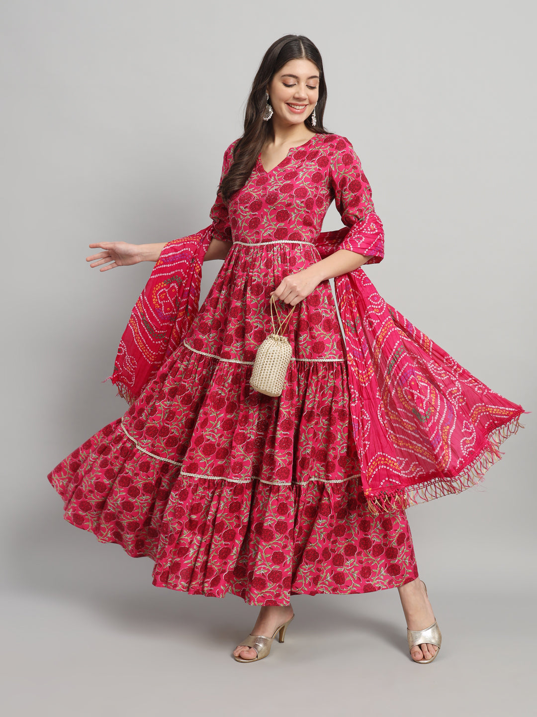 Woman in a pink floral maternity dress with dupatta, posing in front of gray background