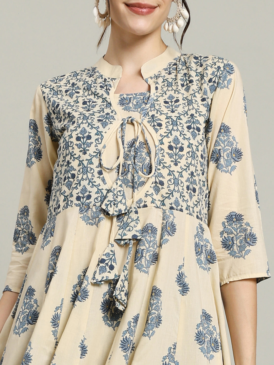 Woman wearing a beige maternity kurta with blue floral print and tie-up neckline