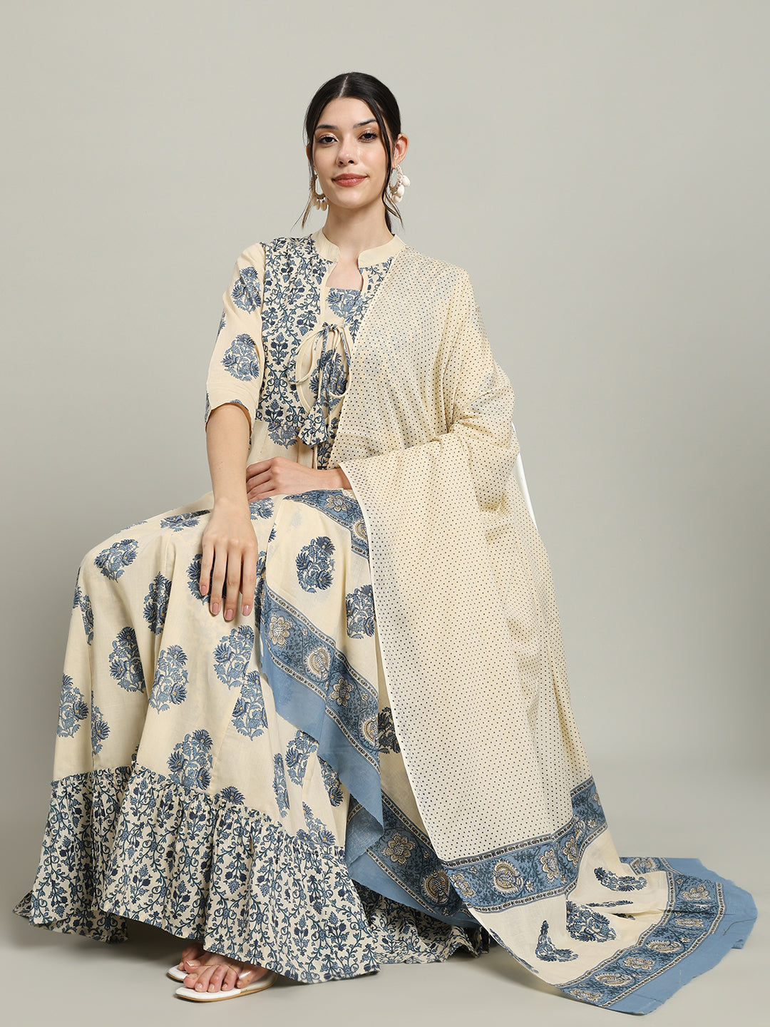 Woman in cream and blue printed maternity dress with dupatta, sitting against plain background