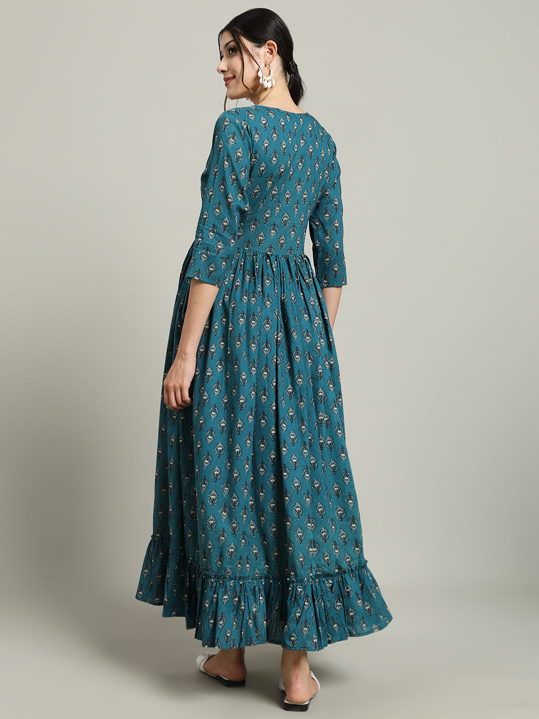 Woman in teal printed maternity maxi dress with three-quarter sleeves and ruffled hem