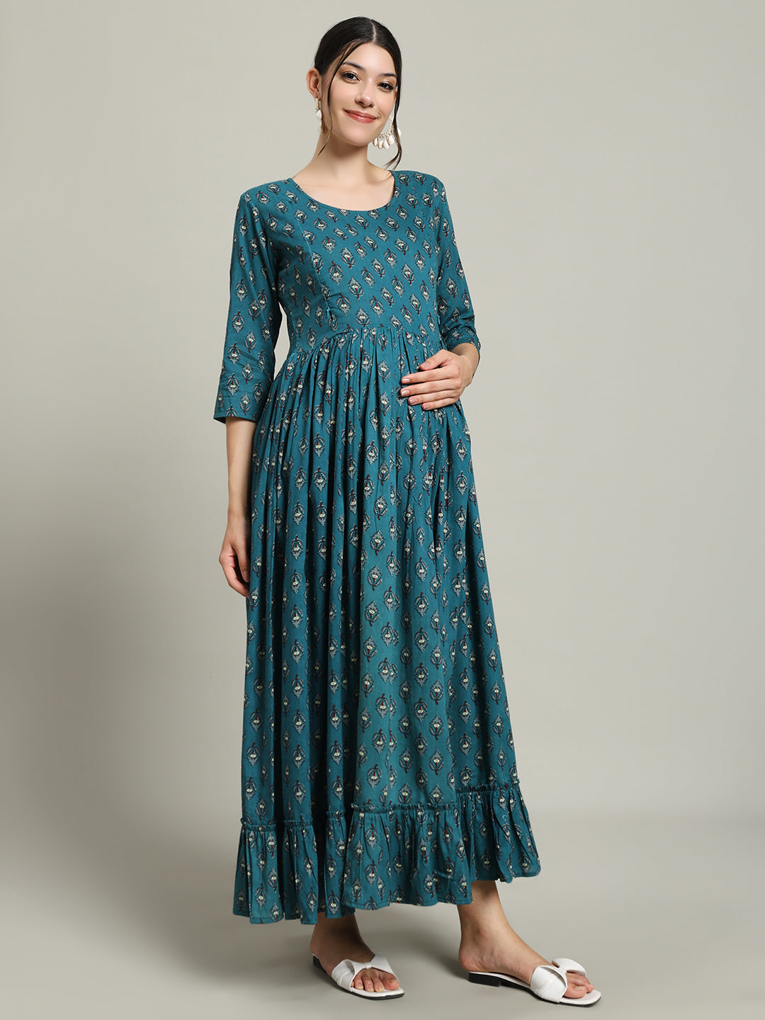Woman wearing teal printed maternity maxi dress with ruffle hem and three-quarter sleeves