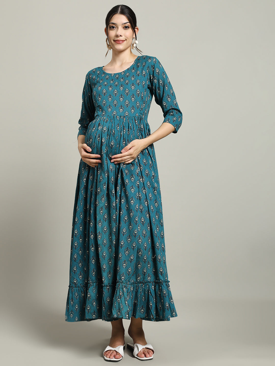 Pregnant woman in teal printed maternity maxi dress with three-quarter sleeves and ruffle hem