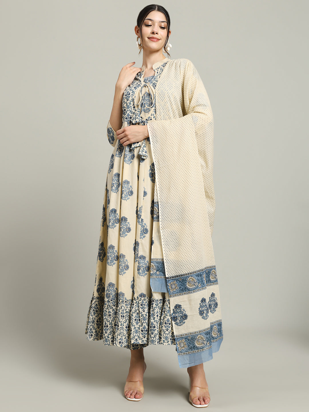 Woman wearing cream and blue floral maternity dress with dupatta, standing against plain background