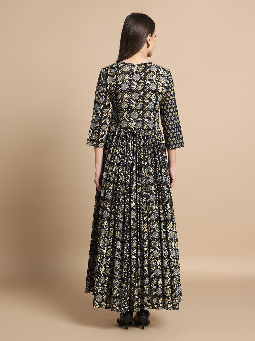 Woman wearing a long black printed maternity maxi dress with three-quarter sleeves, back view