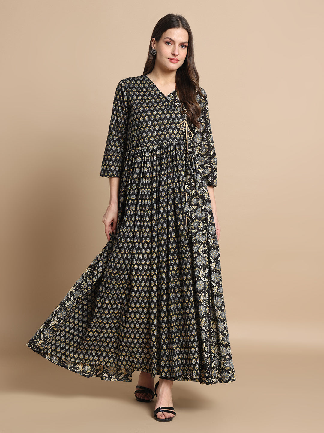 Woman wearing a black printed maternity maxi dress with three-quarter sleeves, standing indoors.