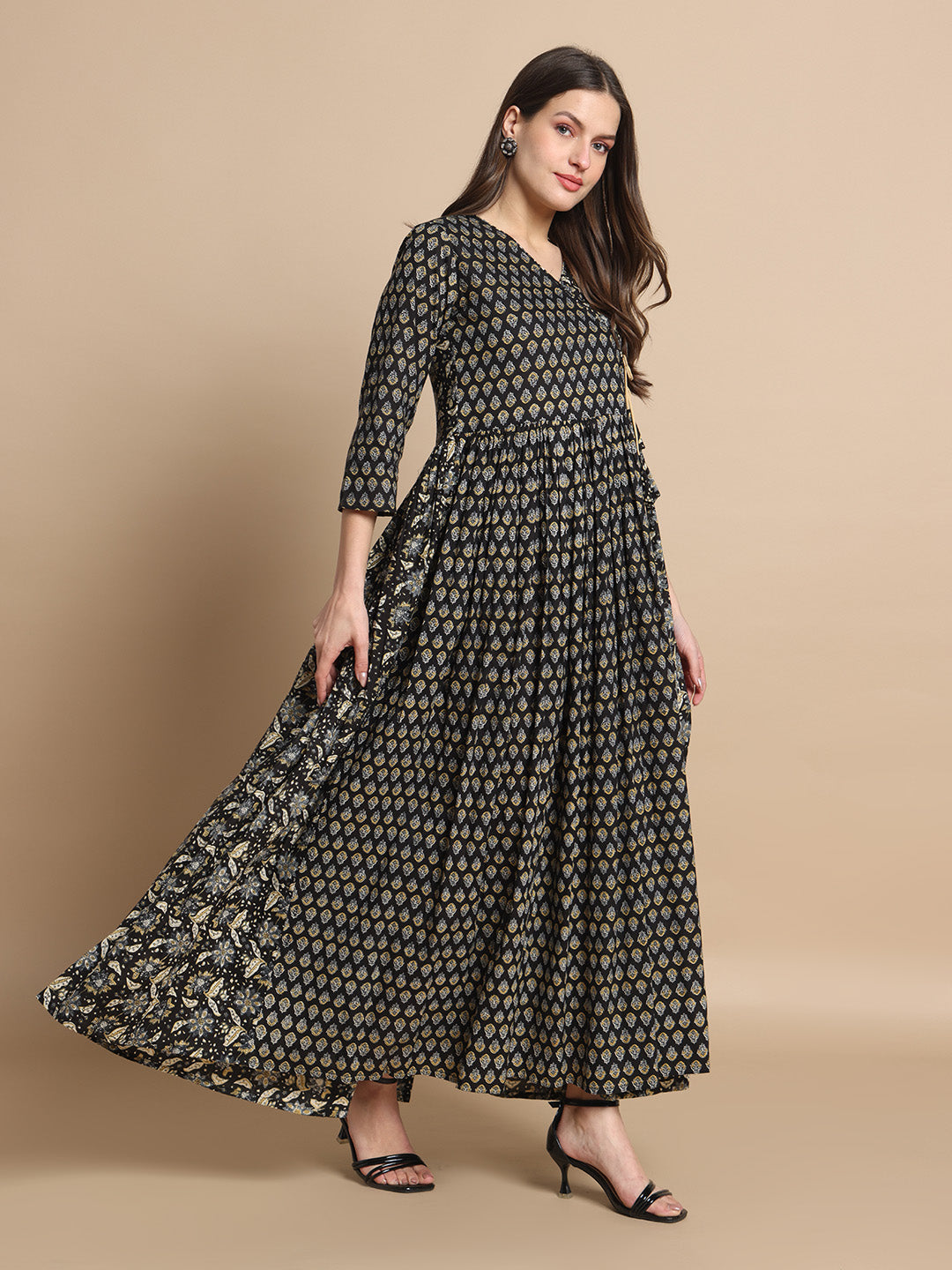 Woman wearing a black and gold printed maternity maxi dress with three-quarter sleeves