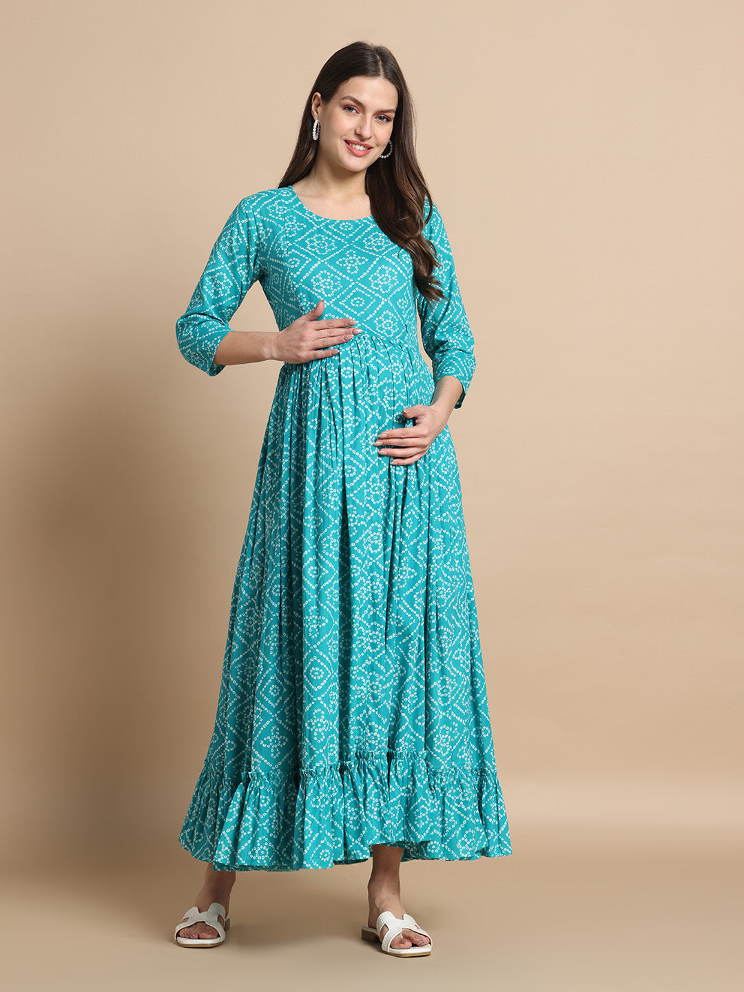 Smiling woman in a teal printed maternity maxi dress with three-quarter sleeves and ruffle hem