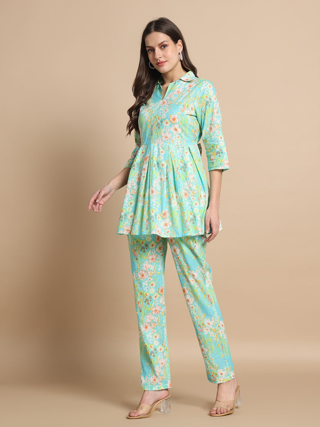 Woman in a floral print maternity kurta set with pastel blue and green colors, standing indoors.