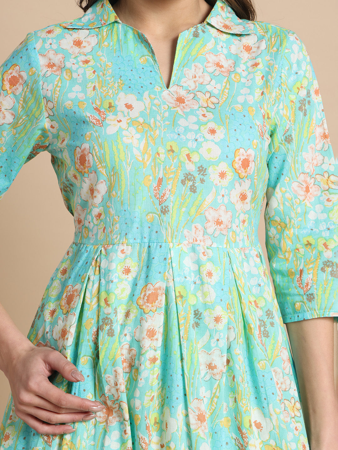 Woman wearing a turquoise floral maternity dress with three-quarter sleeves and pleated waist