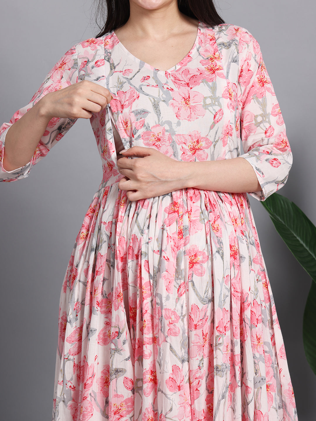 Woman wearing a pink floral nursing dress with front zipper for easy breastfeeding access.