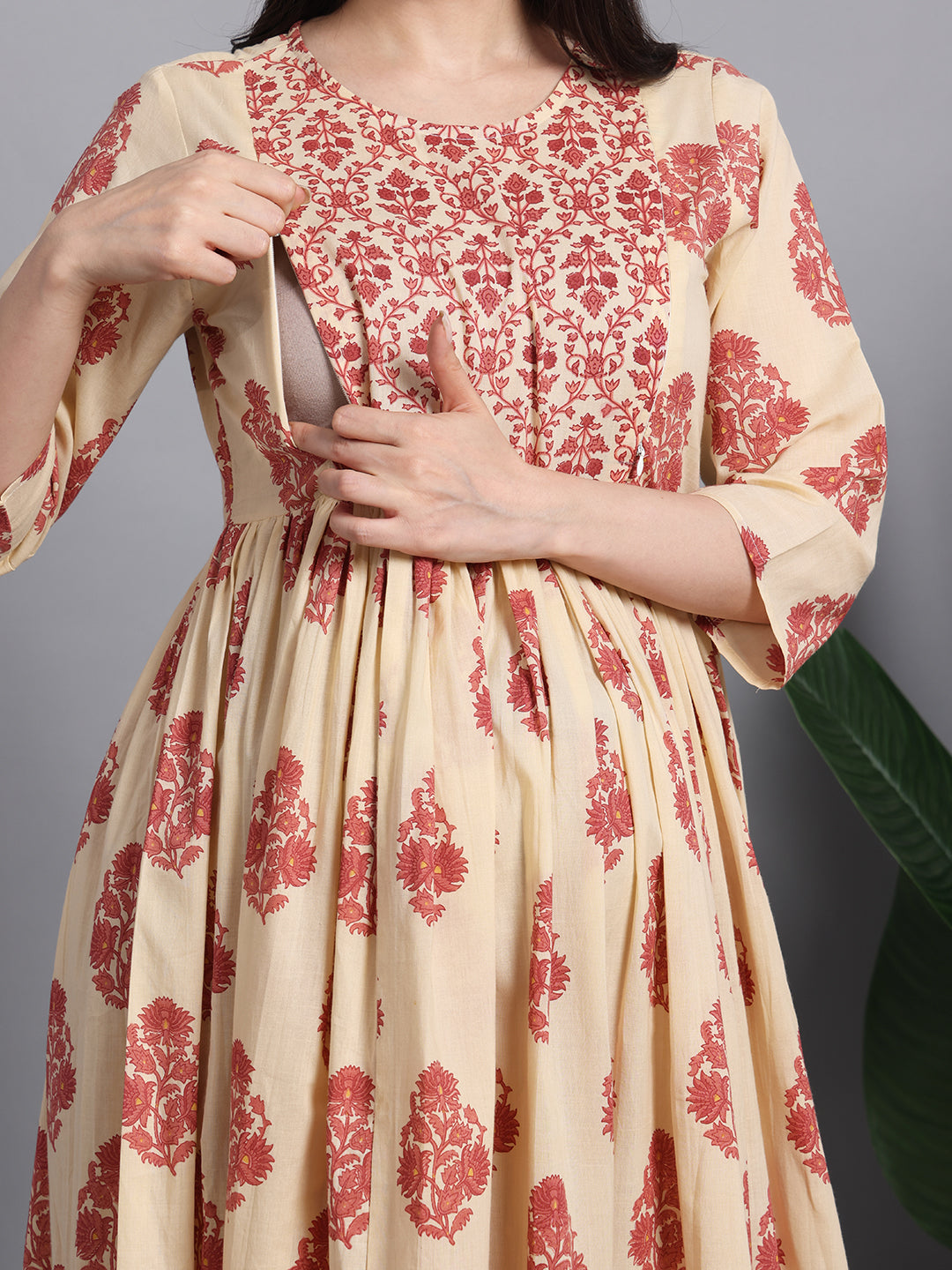 Woman wearing a cream and red floral maternity and nursing dress with discreet zip opening