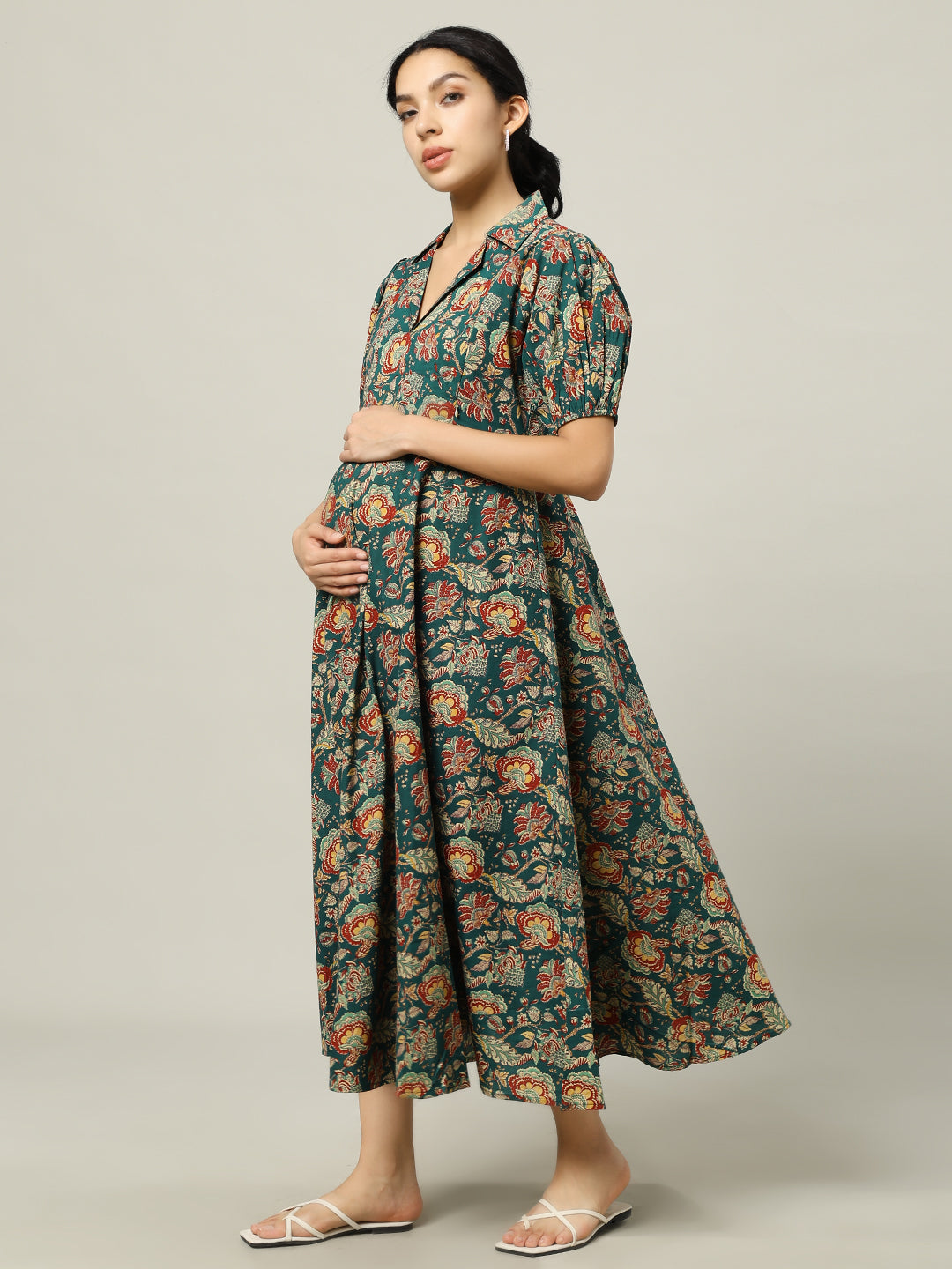 Woman wearing a green floral maternity dress with puff sleeves, holding a brown handbag