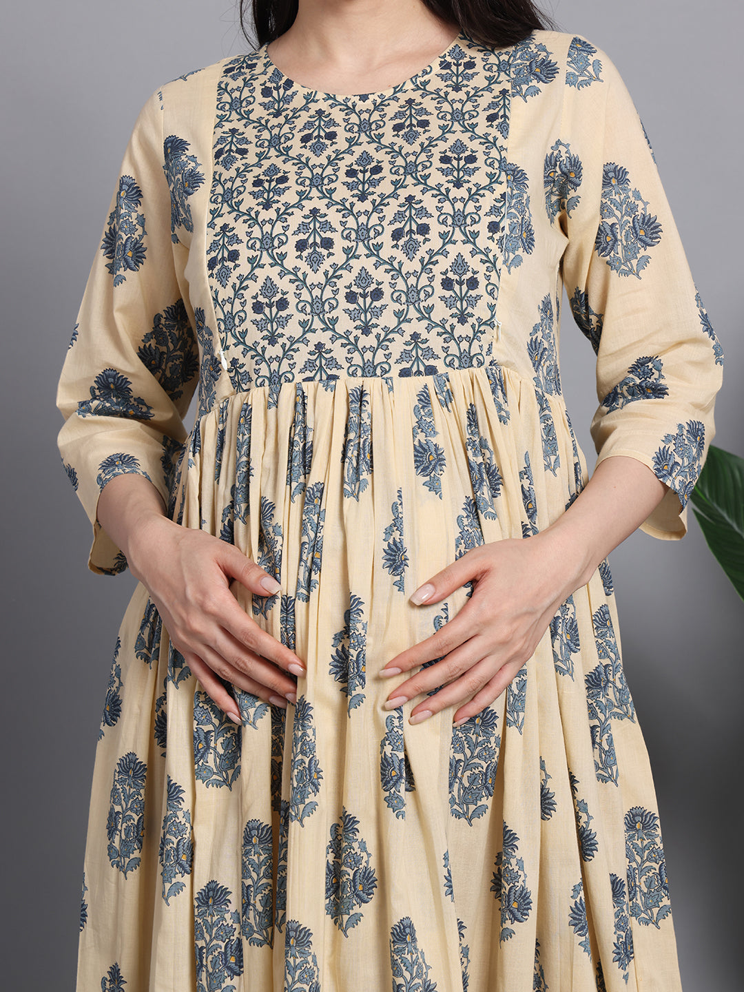 Pregnant woman wearing cream and blue floral print maternity dress with three-quarter sleeves