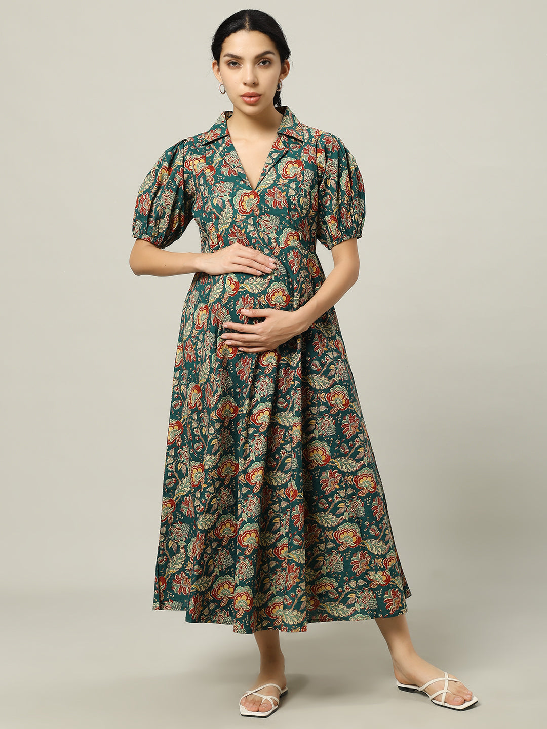 Woman wearing a green floral maternity dress with puff sleeves and V-neck, standing indoors