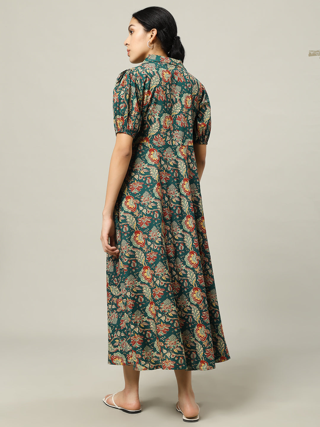 Woman wearing a green floral maternity dress with short sleeves, viewed from the back.
