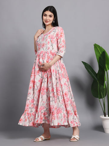 Pregnant woman in pink floral maternity maxi dress, three-quarter sleeves, posing indoors