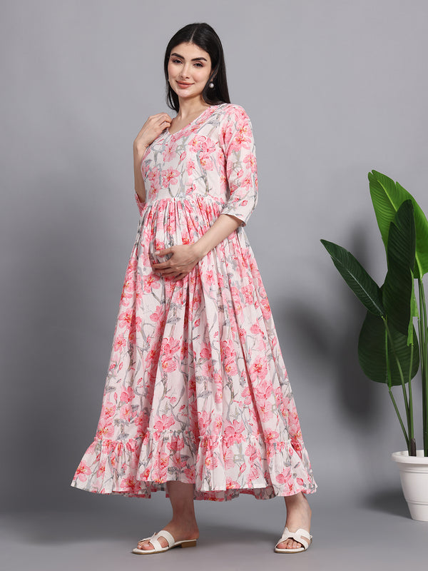 Pregnant woman in pink floral maternity maxi dress, three-quarter sleeves, posing indoors