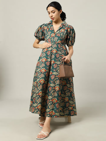 Woman wearing a green floral maternity dress with puff sleeves, holding a brown handbag