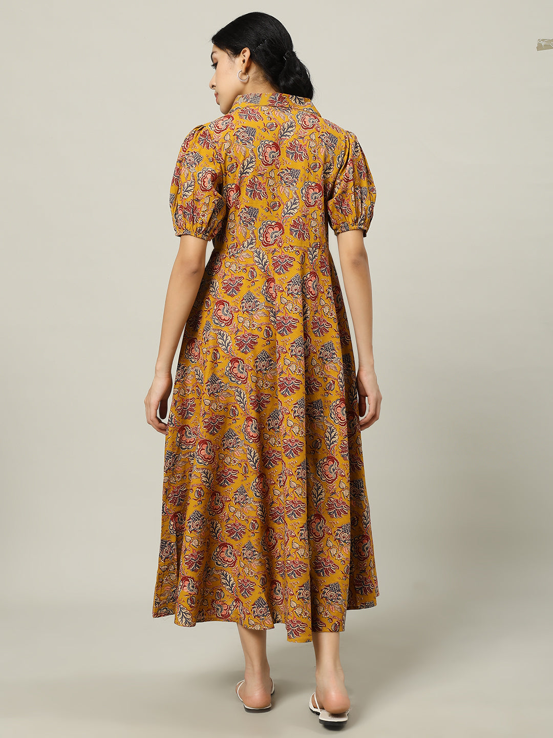 Woman wearing yellow floral print maternity maxi dress with puff sleeves, back view