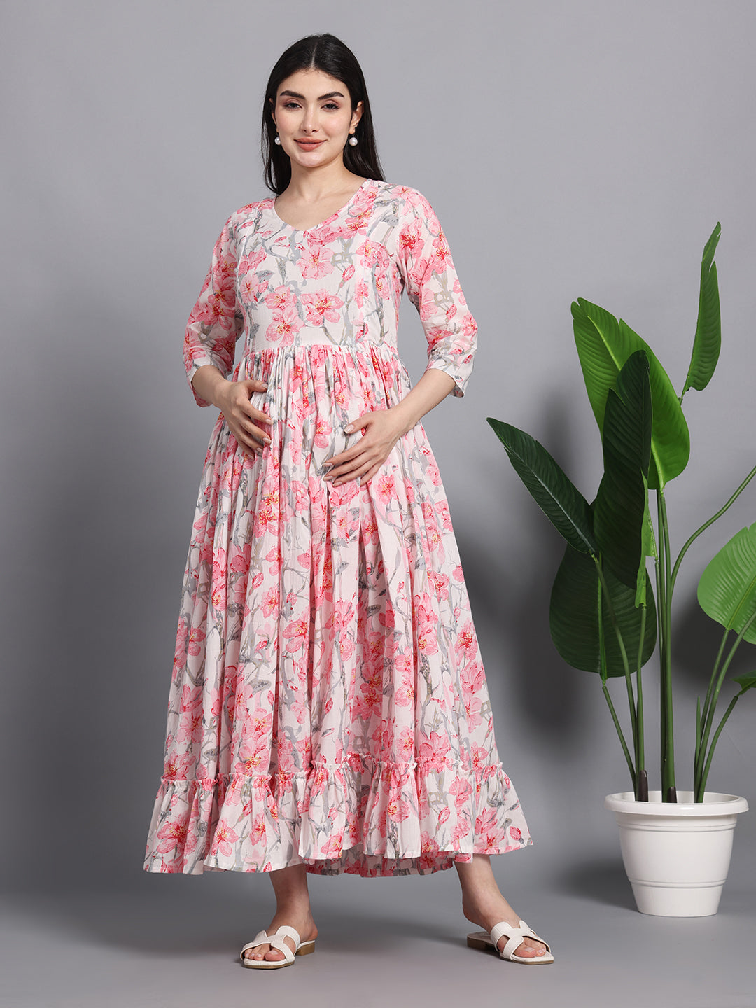 Woman wearing a pink floral maternity maxi dress with 3/4 sleeves, standing indoors