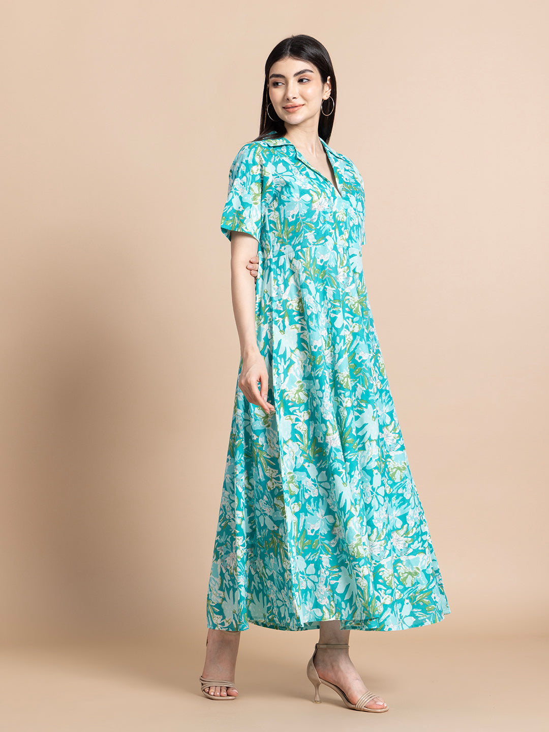 Woman wearing teal floral maternity maxi dress with short sleeves, standing in studio