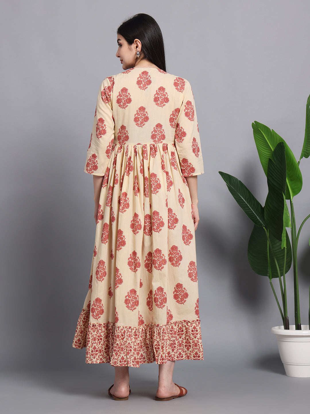 Woman in beige and red floral cotton maternity maxi dress with ruffle hem, indoor setting