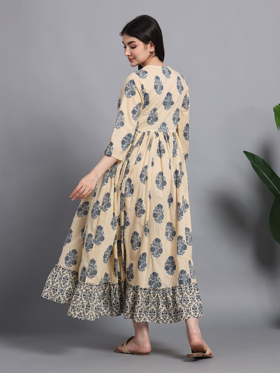 Woman in beige floral maternity maxi dress with printed ruffle hem, side view